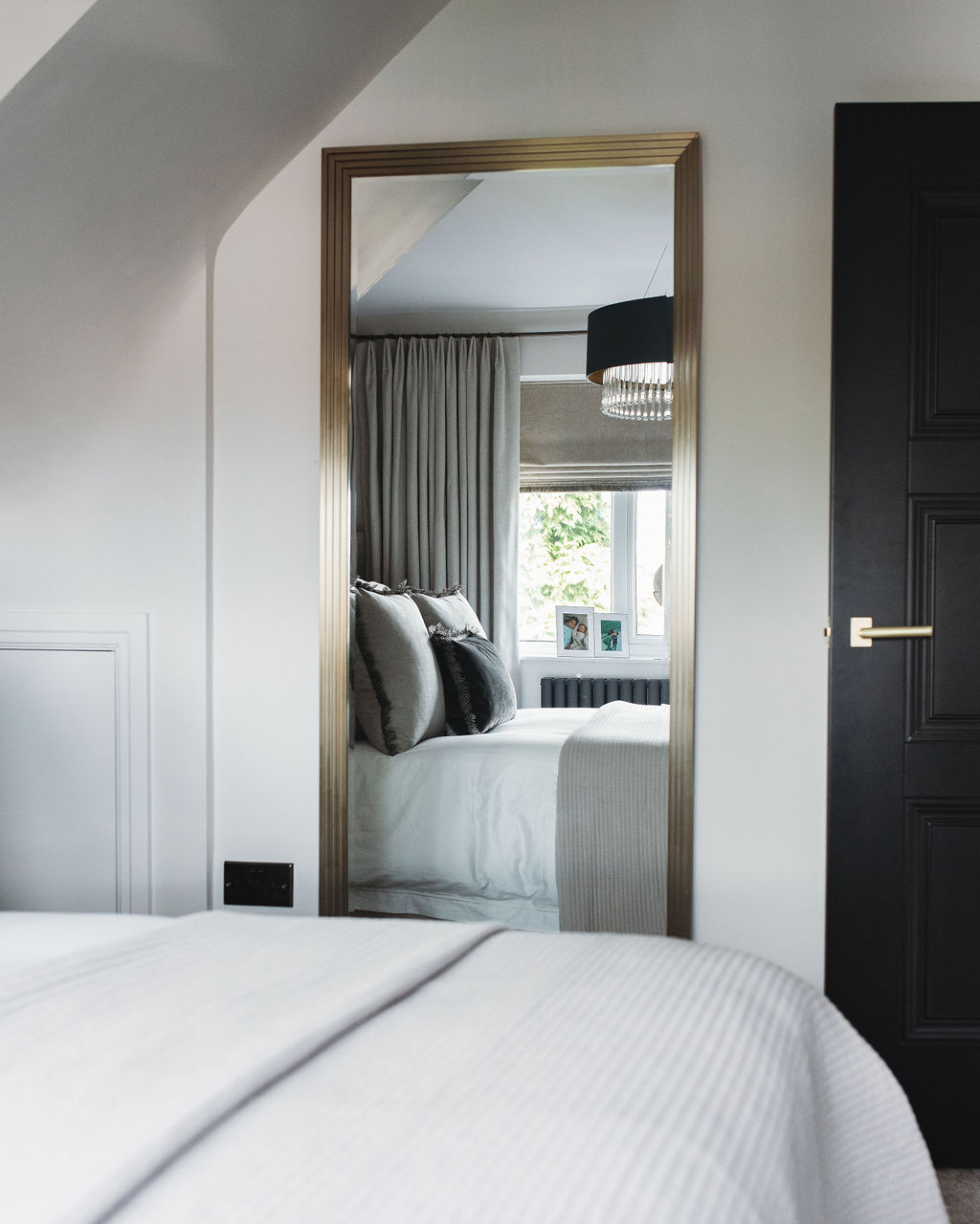 interior design case study image shows a master bedroom reflected in a gold mirror