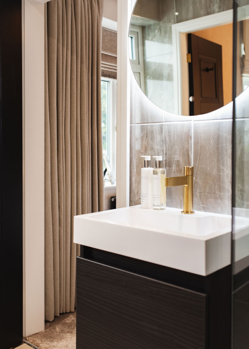 en suite bathroom interior with vanity sink and round mirror