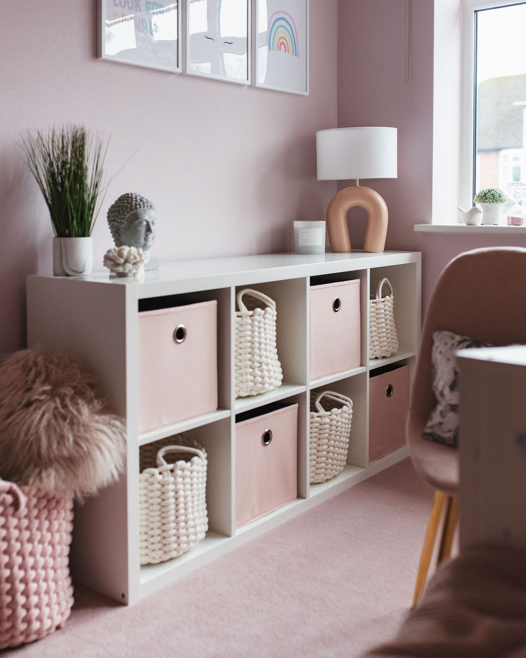 shelving unit in a girls bedroom with pink storage boxes