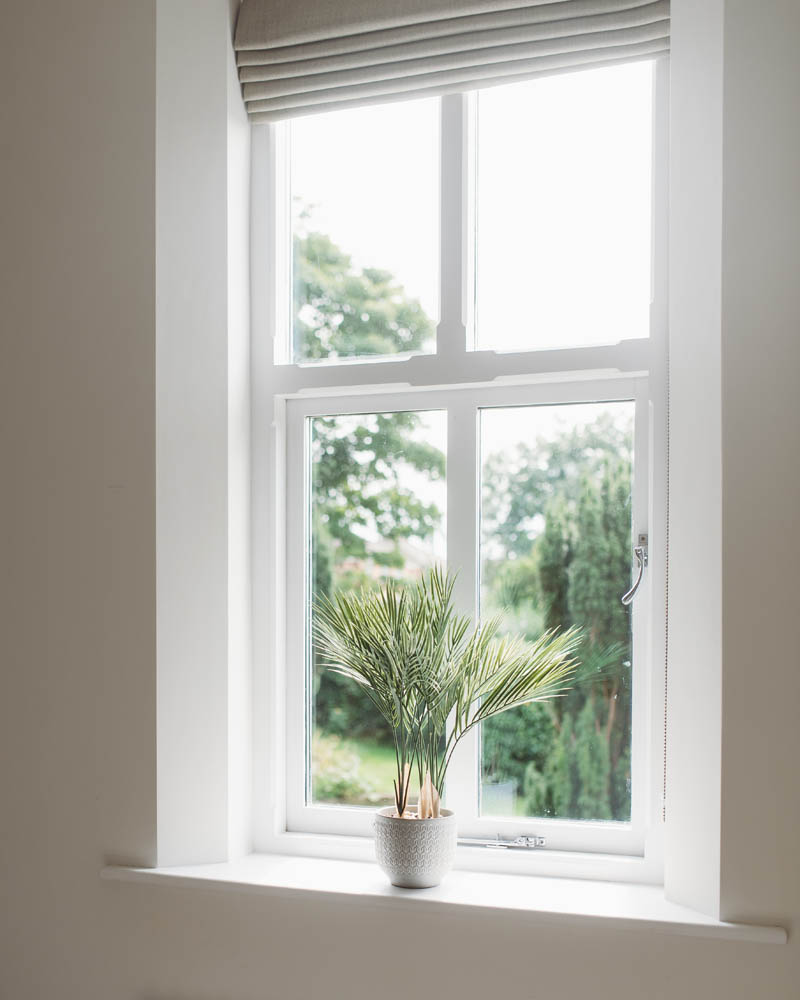 a view of the window with white frame and cream roman blinds